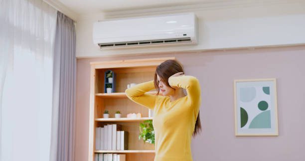 Frustrated man sitting beside a broken and noisy air conditioner unit