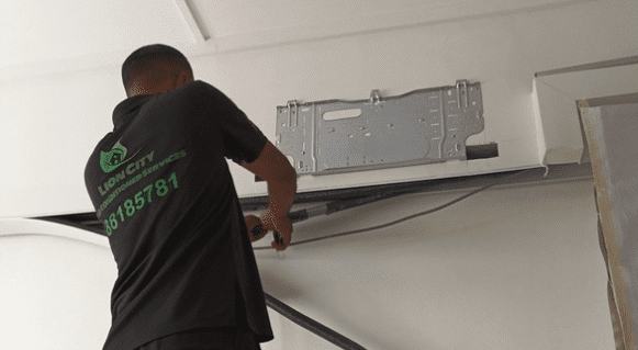 This photo shows a Lion City Air Conditioner Services technician installing an indoor air conditioning unit.