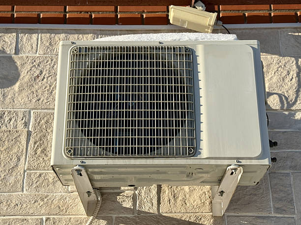 The image features an outdoor condenser unit, serving as a visual reference for troubleshooting mechanical issues. It highlights the importance of identifying abnormal noises to determine what you need to know about whether a loud aircon outdoor unit is dangerous.